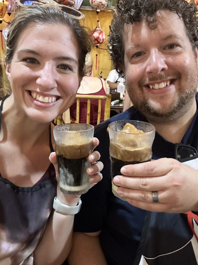 A man and woman holding up coffee while smiling