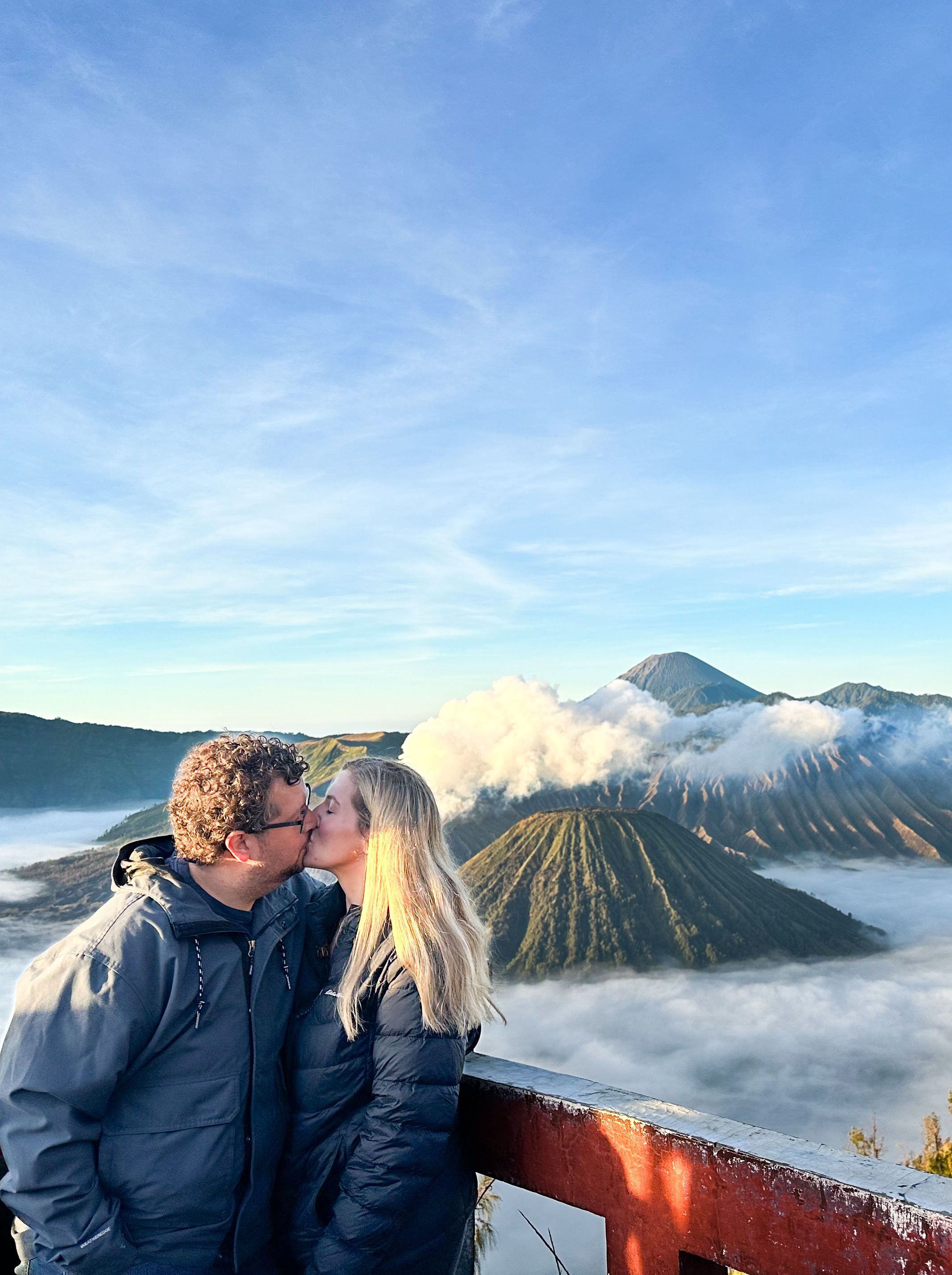 a couple kissing in front of a cloud covered mountain