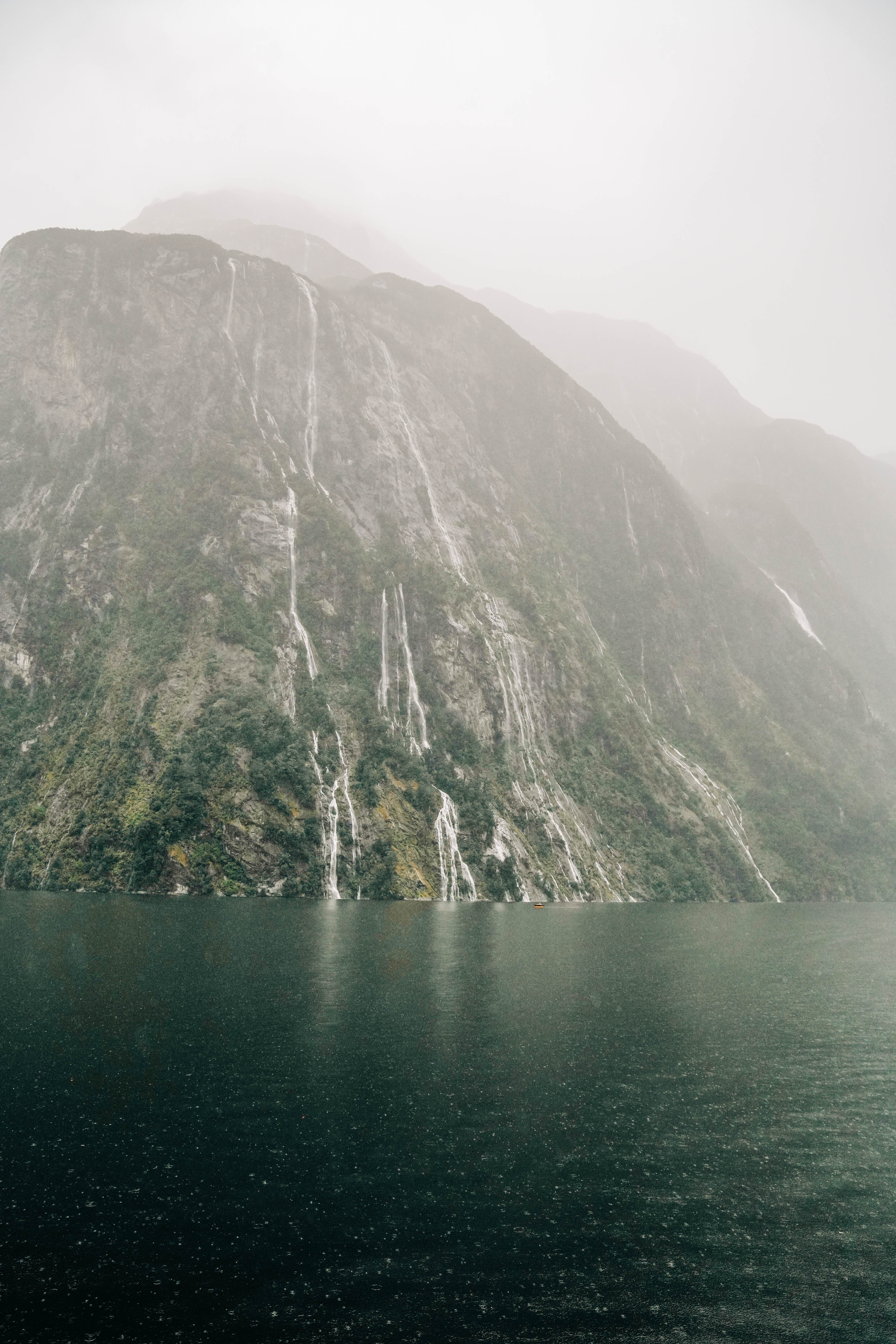 milford sound with water streaming town the fjords during a storm