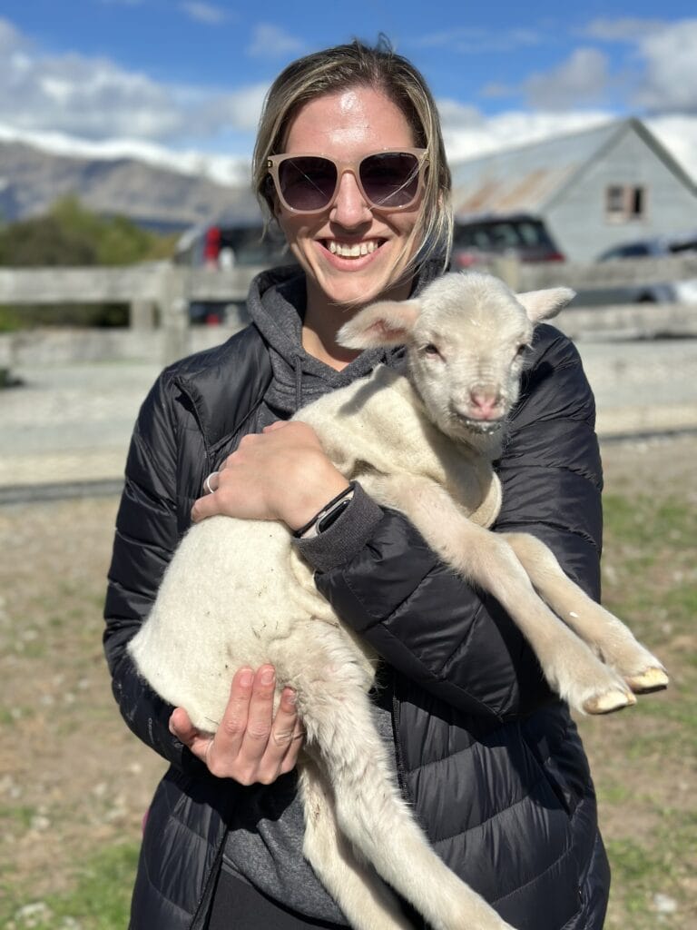 a woman holding a baby goat