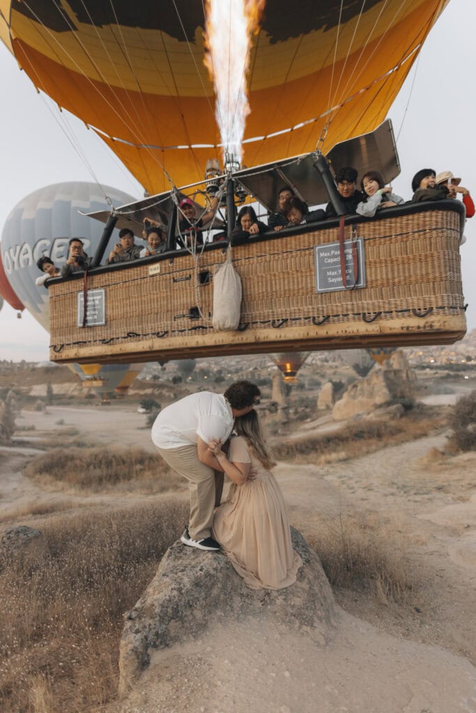 a couple squatting as a hot air balloon goes over them