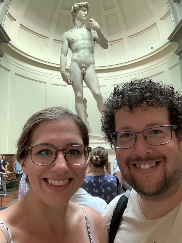 a couple posing with the statue of David in Florence