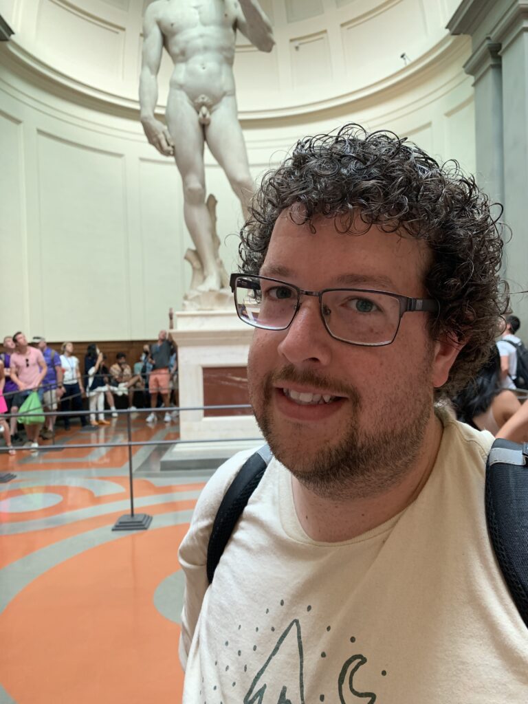 a man posing with the statue of David in Florence