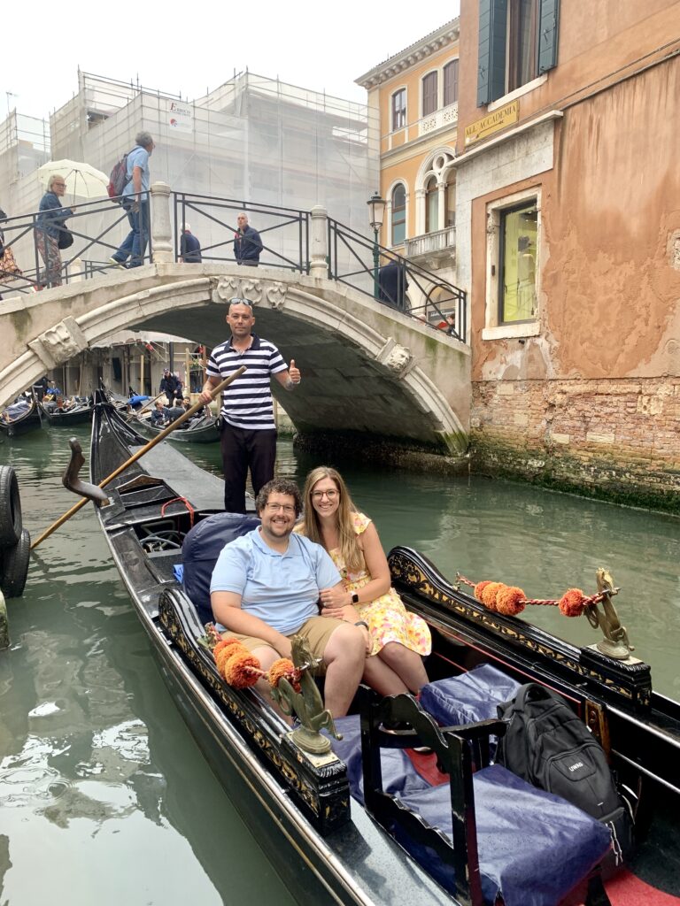 a couple sitting in a gondola with a gondolier rowing them